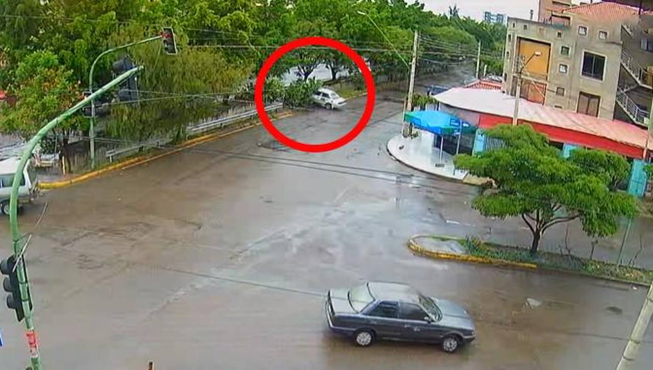 Cámara capta cuando un taxi cae a un canal de drenaje tras pasarse un semáforo en rojo y ser impactado por un minibús