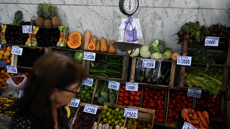 Una mujer pasa junto a un puesto de frutas y verduras en un mercado callejero de Buenos Aires.