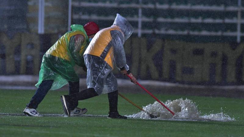 Dos funcionarios intentan sacar el agua del campo de juego del estadio Siles. 