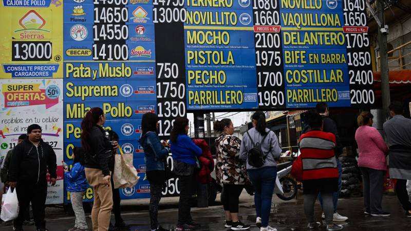 La gente hace fila frente a una carnicería junto a carteles con los precios de la carne en Buenos Aires.