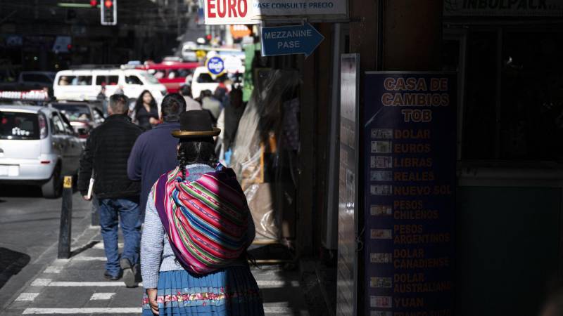 Una mujer circula por una calle en la que se encuentran varias casas de cambio