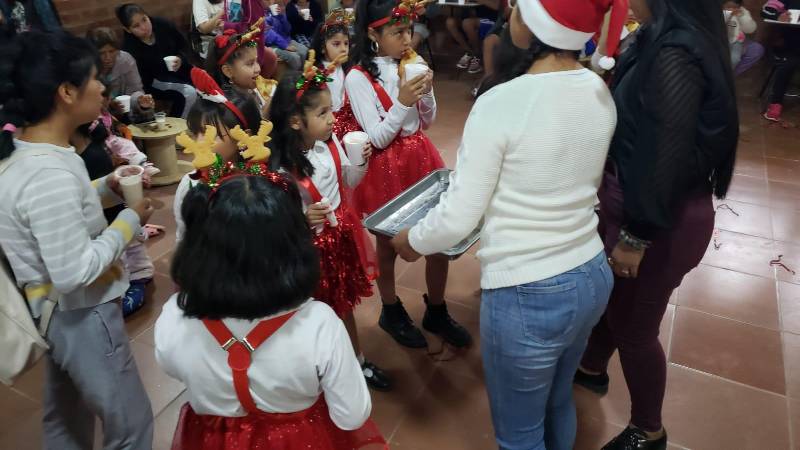 Niños disfrutando de chocolatada navideña.