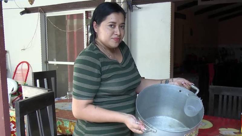 Una vecina muestra cómo deben juntar agua ante la irregularidad del servicio.